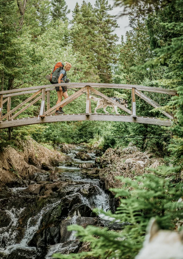 Randonneuse sur une passerelle avec son chien au Parc des Appalaches | Sainte-Lucie-de-Beauregard